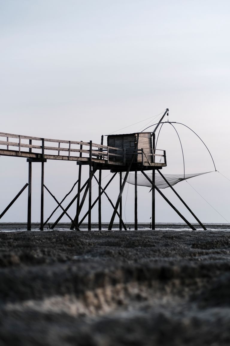 Wooden pier and fishing net at Les Moutiers-en-Retz, France during a tranquil day.