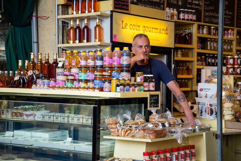 A vibrant market stall showcasing a variety of gourmet products with a thoughtful shopkeeper.